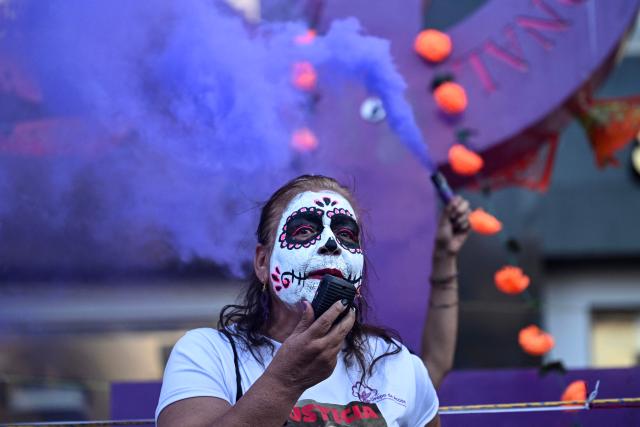 A woman with her face painted as "Catrina" speaks to demonstrators during a protest march to demand the clarification of femicides ahead of the Day of the Dead celebrations in Mexico City on October 31, 2025. (Photo by Yuri CORTEZ / AFP)