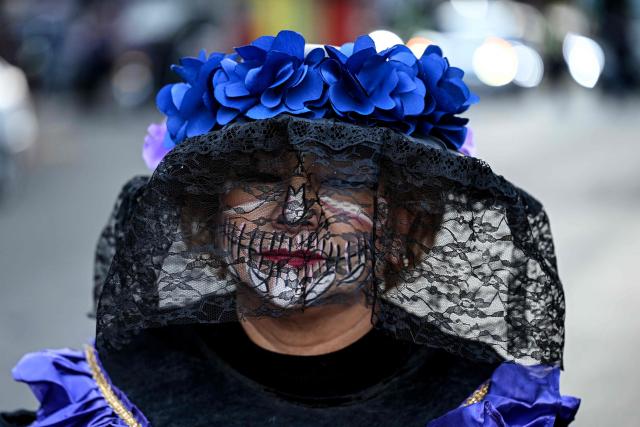 A woman with her face painted as "Catrina" participates in a protest march to demand the clarification of femicides in the context of the Day of the Dead celebrations in Mexico City on October 31, 2025. (Photo by Yuri CORTEZ / AFP)