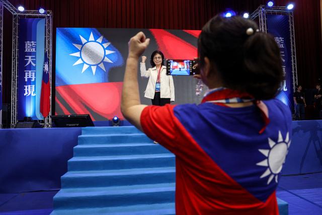 TOPSHOT - Participants pose with Taiwan flags before the Kuomintang (KMT) 12th National Congress in Taipei on November 1, 2025. Taiwan can't afford to hike its defence budget to more than three percent of GDP, the new leader of the democratic island's biggest opposition party told AFP, which could derail the government's spending plans. (Photo by I-Hwa Cheng / AFP)
