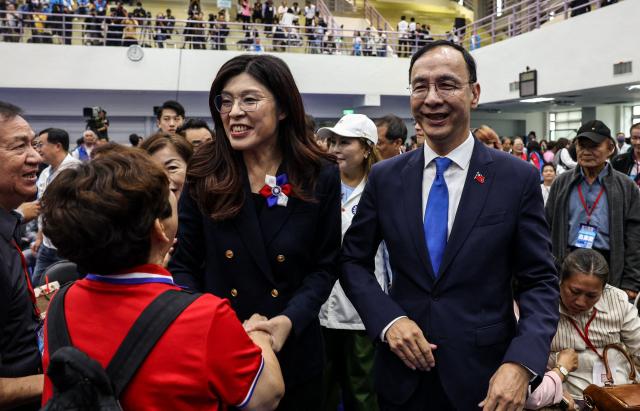Newly elected opposition Kuomintang (KMT) leader Cheng Li-wun (L) shakes hands with supporters as former KMT chairman Eric Chu looks on during the Kuomintang (KMT) 12th National Congress in Taipei on November 1, 2025 (Photo by I-Hwa Cheng / AFP)
