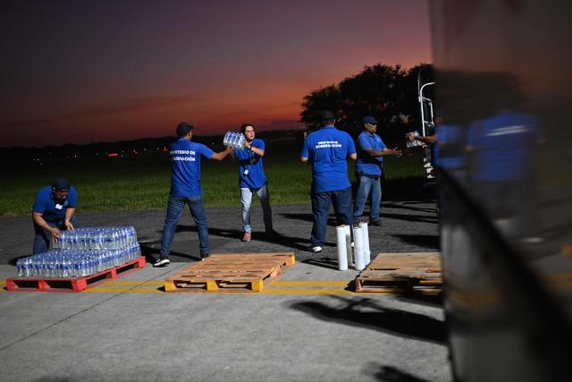 Salvadorean government workers prepare pallets with bottled water to load in a plane with humanitarian aid bound for Jamaica, ordered by El Salvador's President Nayib Bukele, after the passage of Hurricane Melissa, at the tarmac of San Oscar Romero International Airport in San Luis Talpa, El Salvador on October 31, 2025. Melissa, the worst Atlantic hurricane in nearly a century, left at least 30 dead in Haiti and 19 in Jamaica, as well as parts of Cuba in ruins, as it moved through the Caribbean toward Bermuda on Thursday. (Photo by Marvin RECINOS / AFP)