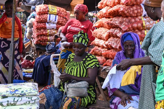Customers shop at a market in Tengrela, northern Ivory Coast near the Mali border, on October 31, 2025. (Photo by Issouf SANOGO / AFP)