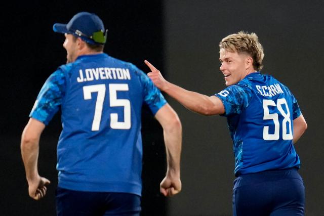 England's Sam Curran (R) celebrates New Zealand's Daryl Mitchell being caught with teammate Jamie Overton during the third one-day international (ODI) cricket match between New Zealand and England at Sky Stadium in Wellington on November 1, 2025. (Photo by Marty MELVILLE / AFP)