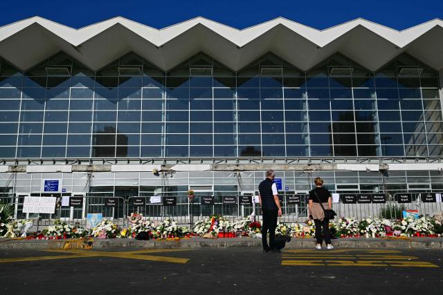 Mourners stand beide layed flowers and candles outside the station during a gathering marking the first anniversary of the Novi Sad railway station tragedy, in Novi Sad, on November 1, 2025. Tens of thousands gather in Serbia's second largest city Novi Sad to commemorate victims of a railway station collapse a year ago that triggered mass protests. On November 1, 2024, the collapse of the canopy at the newly-renovated railway station in Novi Sad killed 16 people. Regular student-led protests have gripped the Balkan nation since the tragedy, which became a symbol of entrenched corruption. (Photo by Andrej ISAKOVIC / AFP)