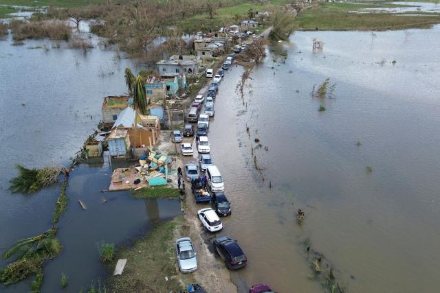 An aerial view shows cars and damaged property in a flooded section of road from Holland Bamboo to Middle Quarters in St Elizabeth, Jamaica, on October 31, 2025. At least 19 people in Jamaica have died as a result of Hurricane Melissa which devastated the island nation when it roared ashore this week, a government minister told news outlets late October 31. (Photo by Ricardo Makyn / AFP)