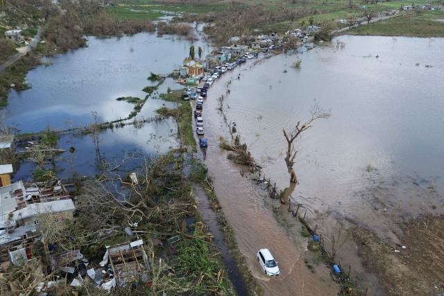 An aerial view shows cars and damaged property in a flooded section of road from Holland Bamboo to Middle Quarters in St Elizabeth, Jamaica, on October 31, 2025. At least 19 people in Jamaica have died as a result of Hurricane Melissa which devastated the island nation when it roared ashore this week, a government minister told news outlets late October 31. (Photo by Ricardo Makyn / AFP)