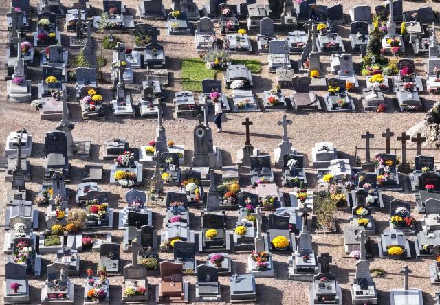 This aerial photograph shows graves decorated with flowers on All Saints' Day in a cemetery in Hede-Bazouges, northwestern France on November 1, 2025. (Photo by Damien MEYER / AFP)