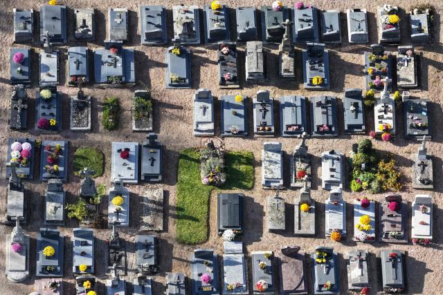 This aerial photograph shows graves decorated with flowers on All Saints' Day in a cemetery in Hede-Bazouges, northwestern France on November 1, 2025. (Photo by Damien MEYER / AFP)