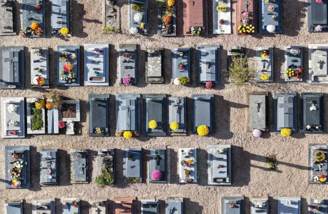 This aerial photograph shows graves decorated with flowers on All Saints' Day in a cemetery in Hede-Bazouges, northwestern France on November 1, 2025. (Photo by Damien MEYER / AFP)