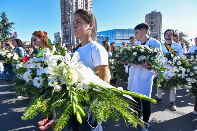 Mourners carry flowers to lay outside the stationduring a gathering marking the first anniversary of the Novi Sad railway station tragedy, in Novi Sad, on November 1, 2025. Tens of thousands gather in Serbia's second largest city Novi Sad to commemorate victims of a railway station collapse a year ago that triggered mass protests. On November 1, 2024, the collapse of the canopy at the newly-renovated railway station in Novi Sad killed 16 people. Regular student-led protests have gripped the Balkan nation since the tragedy, which became a symbol of entrenched corruption. (Photo by Nenad MIHAJLOVIC / AFP)