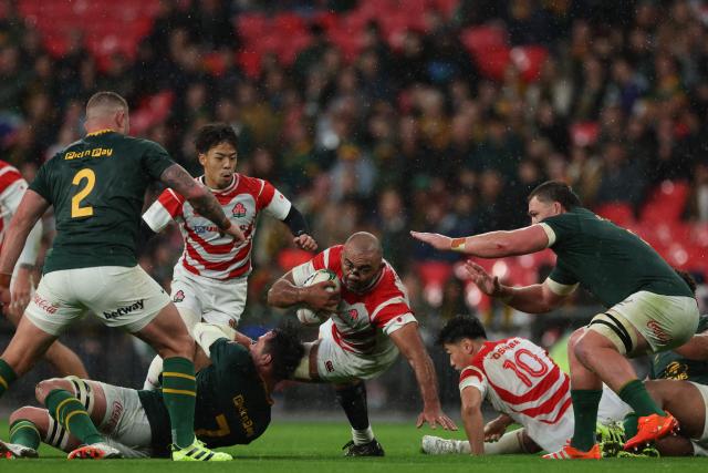 Japan's number 8 Michael Leitch (C) is tackled by South Africa's flanker Franco Mostert (L) during the Autumn Nations Series international rugby union match between South Africa and Japan at Wembley Stadium in north-west London, on November 1, 2025. (Photo by Adrian Dennis / AFP)