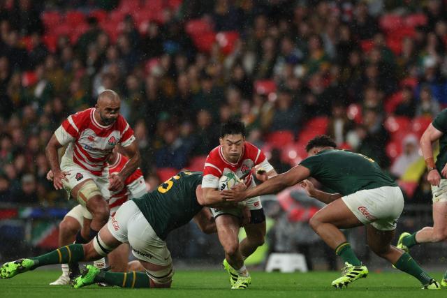 Japan's fly-half Lee Seung-Sin (C) is tackled by South Africa's lock Lood De Jager (L) and South Africa's prop Zachary Porthen (R) during the Autumn Nations Series international rugby union match between South Africa and Japan at Wembley Stadium in north-west London, on November 1, 2025. (Photo by Adrian Dennis / AFP)