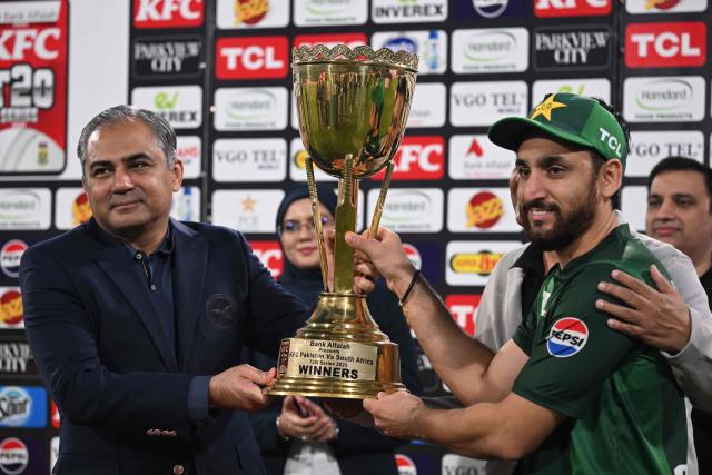 Pakistan's captain Salman Agha (R) receives the winning trophy from Pakistan Cricket Board Chairman Mohsin Naqvi (L) at the end of third and final Twenty20 international cricket match between Pakistan and South Africa at the Gaddafi Stadium in Lahore on November 2, 2025.  (Photo by Farooq NAEEM / AFP)