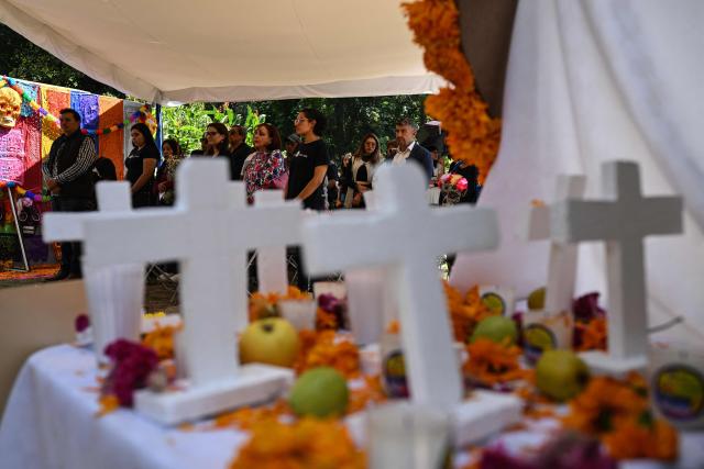 People attend a mass in memory of individuals buried as unknown in a mass grave at the Dolores Cemetery in Mexico City, on November 1, 2025, during an event organized by the National Search Commission (CNB), El Caracol A.C., and other civil society groups. (Photo by Yuri CORTEZ / AFP)