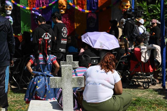 People attend a mass in memory of individuals buried as unknown in a mass grave at the Dolores Cemetery in Mexico City, on November 1, 2025, during an event organized by the National Search Commission (CNB), El Caracol A.C., and other civil society groups. (Photo by Yuri CORTEZ / AFP)