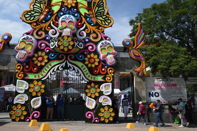 People arrive carrying flowers to visit the graves of their loved ones at the Dolores Cemetery as part of Day of the Dead celebrations in Mexico City, on November 1, 2025. (Photo by Yuri CORTEZ / AFP)