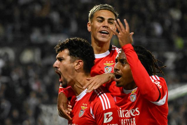 SL Benfica's Portuguese defender #44 Tomas Araujo (L) celebrates scoring his team's first goal with Luxembourgish midfielder #18 Leandro Barreiro (R) and Argentine midfielder #05 Enzo Barrenechea during the Portuguese League football match between Vitoria Guimaraes SC and SL Benfica at Dom Afonso Henriques stadium in Guimaraes on November 1, 2025. (Photo by Miguel RIOPA / AFP)