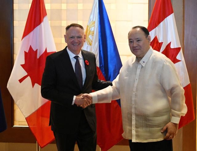 Philippines' Secretary of National Defence Gilberto Teodoro (R) shakes hands with Canadian Minister of Defence David McGuinty prior to their bilateral meeting in Manila on November 2, 2025.  (Photo by Ted ALJIBE / AFP)