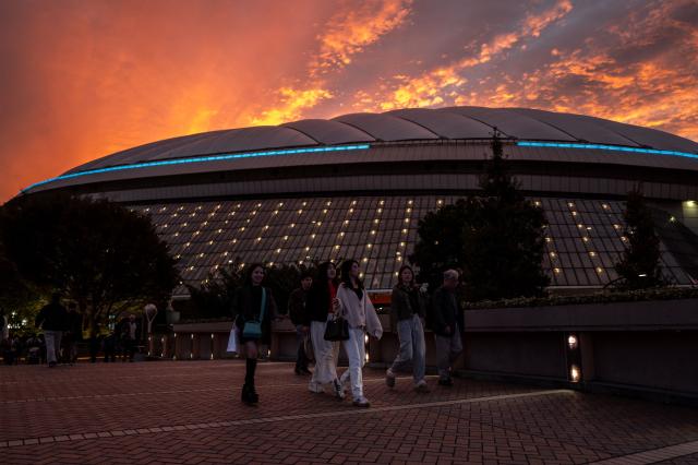 People walk at the Tokyo Dome City during evening hour in Bunkyo district of Tokyo on November 2, 2025. (Photo by Philip FONG / AFP)