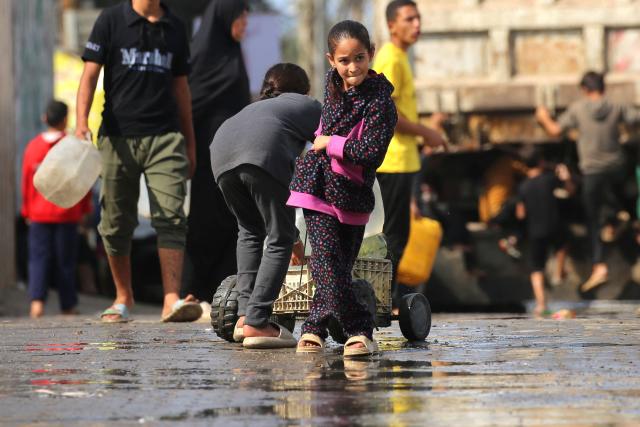 A Palestinian girl pulls a trolley carrying large plastic bottle filled with water, after collecting it at a camp for displaced people, in the Nuseirat refugee camp, located in the central Gaza Strip, on November 2, 2025. (Photo by EYAD BABA / AFP)