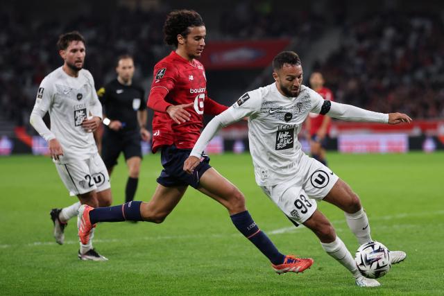 Lille's French midfielder #32 Ayyoub Bouaddi (C) fights for the ball with Angers' Algerian midfielder #93 Haris Belkebla (R) during the French L1 football match between LOSC Lille and Angers SCO at Stade Pierre-Mauroy in Villeneuve-d'Ascq, near Lille on November 2, 2025. (Photo by Anne-Christine POUJOULAT / AFP)