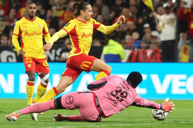 Lorient's Swiss goalkeeper #38 Yvon Mvogo (bottom) dives to block Lens' French forward #10 Florian Thauvin (C) during the French L1 football match between RC Lens and FC Lorient at the Stade Bollaert-Delelis in Lens, northern France, on November 2, 2025. (Photo by Francois LO PRESTI / AFP)