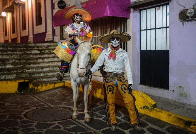A couple dressed as La Catrina and El Catrin pose in the street during the Day of the Dead celebration in Naolinco de Victoria, Veracruz state, Mexico on November 2, 2025. (Photo by Antonio Martinez / AFP)