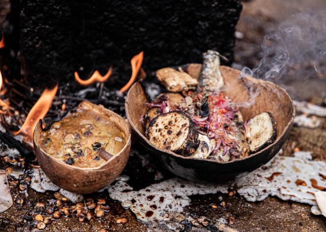 Food brought by people attending Fet Gede, the traditional Haitian Day of the Dead celebration, rest around fire at the Port-au-Prince cemetery, in Haiti, on November 2, 2025. Fet Gede is the annual celebration when practitioners of voodoo parade and believe to be possessed by the spirits of the dead. (Photo by Clarens SIFFROY / AFP)