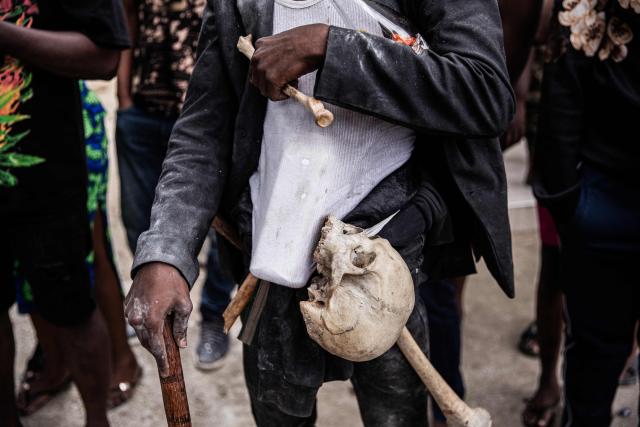 A man carries a human bones as he attends Fet Gede, the traditional Haitian Day of the Dead celebration at the Port-au-Prince cemetery, in Haiti, on November 2, 2025. Fet Gede is the annual celebration when practitioners of voodoo parade and believe to be possessed by the spirits of the dead. (Photo by Clarens SIFFROY / AFP)