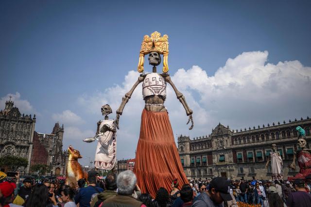 People look at huge statues in Mexico City's Zocalo during the annual Day of the Dead celebrations on November 2, 2025. (Photo by CARL DE SOUZA / AFP)