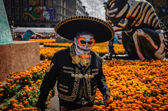 A man in costume walks past marigolds during the annual Day of the Dead celebrations in Mexico City on November 2, 2025. (Photo by CARL DE SOUZA / AFP)