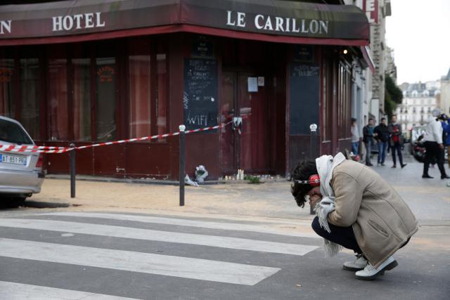 (FILES) A woman mourns outside the Carillon bar in the 10th district of Paris on November 14, 2015, following a series of attacks in and around the city, leaving at least 120 people killed. November 15, 2025 will mark the tenth anniversary of the November 13 attacks, a series of gun attacks that occurred across Paris and outside the national stadium (Stade de France) in Saint-Denis, North of Paris, on November 13, 2015. (Photo by Kenzo TRIBOUILLARD / AFP)