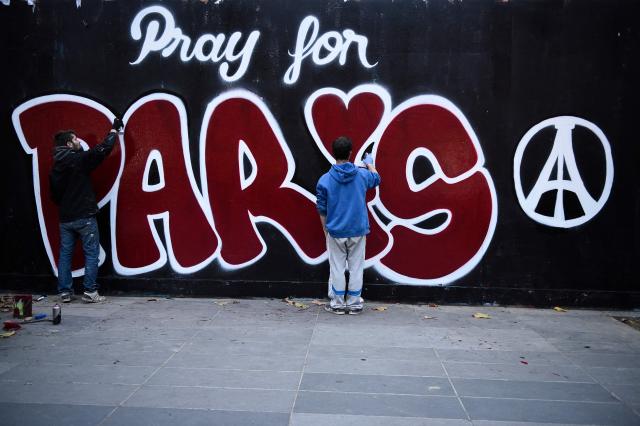 (FILES) Two men paint a mural reading "Pray for Paris" in tribute to the victims of the Paris' attacks on November 14, 2015 in Paris. November 15, 2025 will mark the tenth anniversary of the November 13 attacks, a series of gun attacks that occurred across Paris and outside the national stadium (Stade de France) in Saint-Denis, North of Paris, on November 13, 2015. (Photo by Martin BUREAU / AFP)