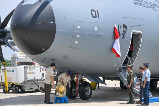 Indonesian President Prabowo Subianto (2nd L) pours holy water alongside Indonesian Defence Minister Sjafrie Sjamsoedin (L) and Indonesian Military Chief General Agus Subiyanto (3rd R) during a handover ceremony of one of two Airbus A-400M military transport aircraft to the Indonesian Air Force at Halim air base in Jakarta on November 3, 2025. (Photo by BAY ISMOYO / AFP)