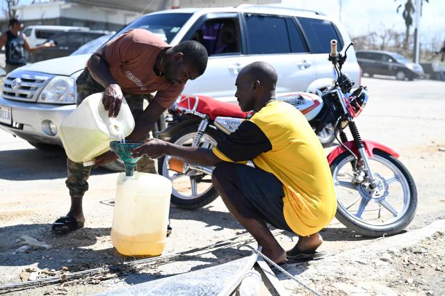 A motorcyclist and a car driver transfer gasoline between jerricans at the roadside in Westmoreland, Jamaica, following the passage of Hurricane Melissa, on November 2, 2025. Planes and helicopters carrying humanitarian aid headed to Jamaica on October 31, three days after Melissa slammed into the island nation and killed at least 19 people.
Information Minister Dana Morris Dixon told a briefing that authorities had "quite credible" reports of possibly five additional deaths but had not yet been able to confirm. (Photo by Ricardo Makyn / AFP)