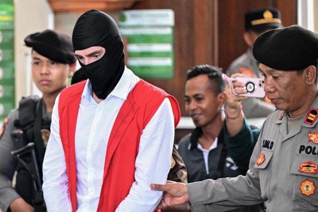 Australian suspect Darcy Francesco Jenson is escorted by the police out of a courtroom after attending a hearing as part of his trial in Denpasar on Indonesia's resort island of Bali on November 3, 2025. The trial of three Australians accused of plotting the murder of a compatriot at a villa in Bali began on October 30, 2025, with all facing the death penalty. (Photo by SONNY TUMBELAKA / AFP)