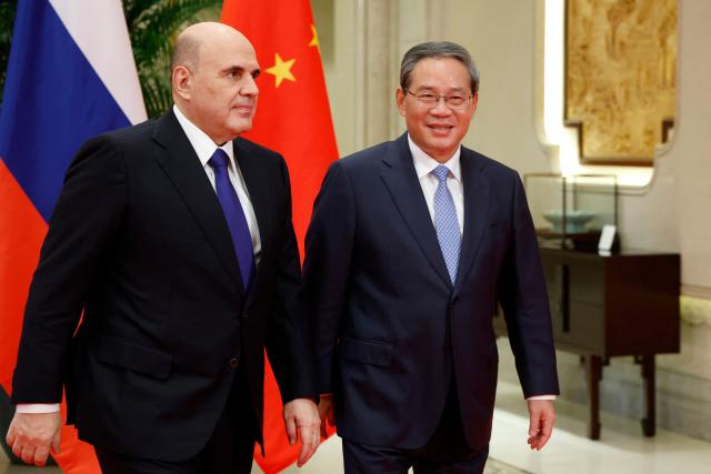 In this pool photograph distributed by the Russian state agency Sputnik, Chinese Premier Li Qiang (R) welcomes Russian Prime Minister Mikhail Mishustin in Hangzhou on November 3, 2025. (Photo by Dmitry ASTAKHOV / POOL / AFP)