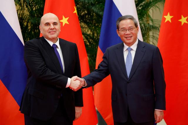 In this pool photograph distributed by the Russian state agency Sputnik, Russian Prime Minister Mikhail Mishustin and Chinese Premier Li Qiang (R) shake hands before their meeting in Hangzhou on November 3, 2025. (Photo by Dmitry ASTAKHOV / POOL / AFP)