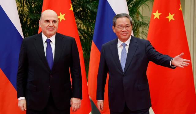 In this pool photograph distributed by the Russian state agency Sputnik, Russian Prime Minister Mikhail Mishustin and Chinese Premier Li Qiang (R) pose for a picture before their meeting in Hangzhou on November 3, 2025. (Photo by Dmitry ASTAKHOV / POOL / AFP)