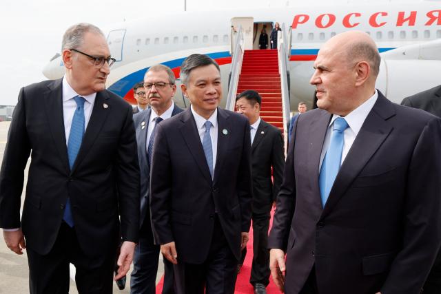 In this pool photograph distributed by the Russian state agency Sputnik, Russian Prime Minister Mikhail Mishustin (R) arrives at the airport of Hangzhou on November 3, 2025. (Photo by Dmitry ASTAKHOV / POOL / AFP)