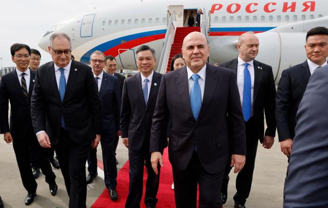 In this pool photograph distributed by the Russian state agency Sputnik, Russian Prime Minister Mikhail Mishustin (C) arrives to the airport of Hangzhou on November 3, 2025. (Photo by Dmitry ASTAKHOV / POOL / AFP)
