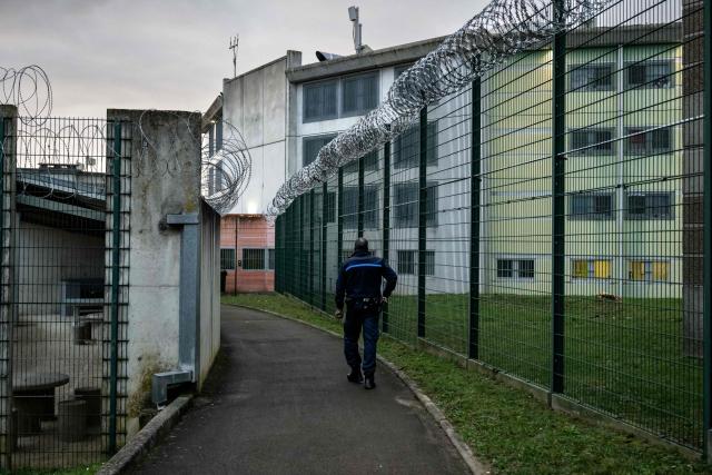 A prison guard walks by barbwire fences at the Villenauxe-La-Grande prison in Villenauxe-La-Grande, northeastern France on November 3, 2025. (Photo by ARNAUD FINISTRE / AFP)