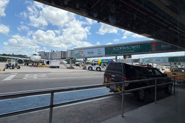 An aircraft stands on the tarmac at International Airport/Val-de-Cans–Julio Cezar Ribeiro with boarding gates decorated with references to COP30 in Belem, Para State, Brazil, on November 3, 2025. (Photo by Pablo PORCIUNCULA / AFP)