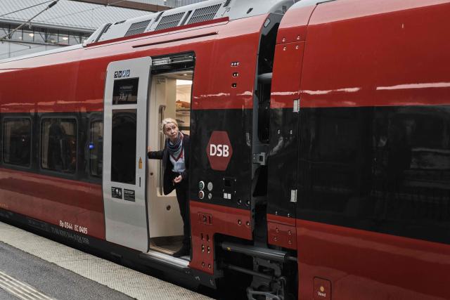 A train conductress looks out of the door of a new EuroCity train carriage of Denmark's national rail operator DSB prior to its first trip departing from Copenhagen on November 3, 2025. DSB's new EuroCity carriages will run on the route between Copenhagen Central Station and Hamburg Central Station. (Photo by Thomas Traasdahl / Ritzau Scanpix / AFP) / Denmark OUT