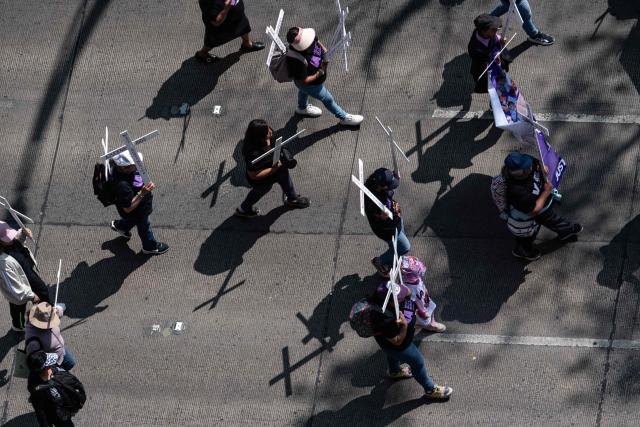Members of the feminist collective "Voces de la Ausencia" carry crosses during a march called "Day of the Women Dead" in memory of women killed in gender-based violence and femicides, and to demand justice and reparations for indirect victims, in Mexico City on November 3, 2025. (Photo by Yuri CORTEZ / AFP)