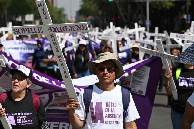 Members of the feminist collective "Voces de la Ausencia" carry crosses during a march called "Day of the Women Dead" in memory of women killed in gender-based violence and femicides, and to demand justice and reparations for indirect victims, in Mexico City on November 3, 2025. (Photo by Yuri CORTEZ / AFP)