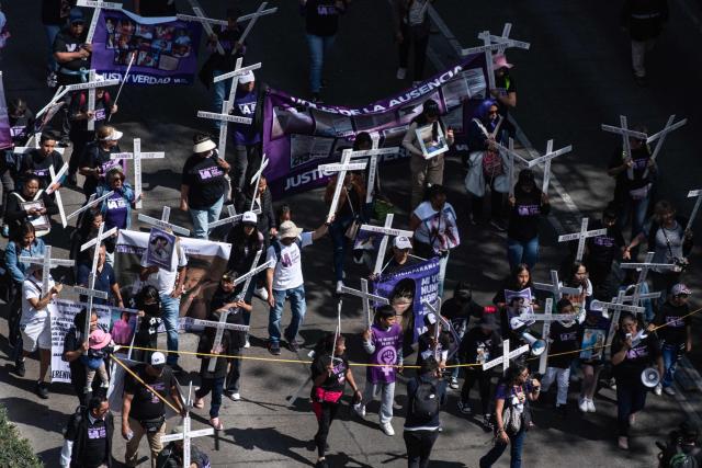 Members of the feminist collective "Voces de la Ausencia" carry crosses during a march called "Day of the Women Dead" in memory of women killed in gender-based violence and femicides, and to demand justice and reparations for indirect victims, in Mexico City on November 3, 2025. (Photo by Yuri CORTEZ / AFP)