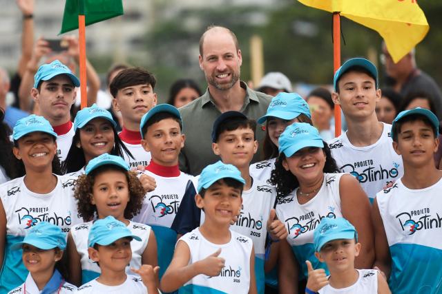 Britain's Prince William (C), Prince of Wales, poses for a picture with children from a social project at a meeting with first responder lifeguards at Copacabana Beach in Rio de Janeiro, Brazil, on November 3, 2025. Prince William visits Brazil to host the Earthshot Prize awards and will later attend the UN COP30 climate summit on behalf of King Charles. (Photo by Daniel RAMALHO / AFP)