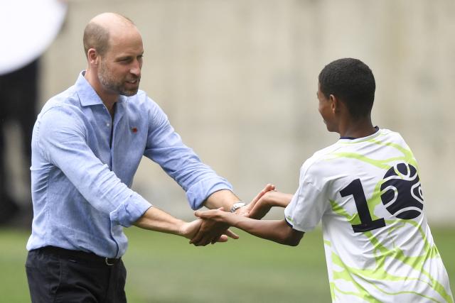 Britain's Prince William (L), Prince of Wales, high-fives a boy taking part in social projects during the "Community Football" event at Maracana Stadium in Rio de Janeiro, Brazil, on November 3, 2025. Prince William visits Brazil to host the Earthshot Prize awards and will later attend the UN COP30 climate summit on behalf of King Charles. (Photo by Daniel RAMALHO / AFP)