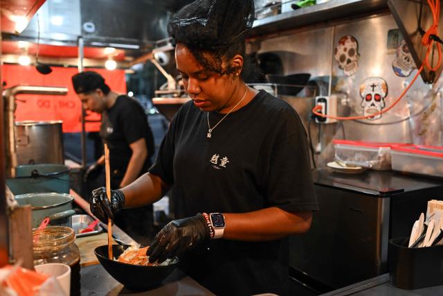 A cook from the Japanese food stall "Chido" prepares ramen, a traditional Japanese noodle dish, in Mexico City on October 29, 2025. While millions celebrate Mexico hosting the FIFA World Cup for a third time, entire families of street vendors watch with concern as the football festivities threaten their long-standing source of income. (Photo by Yuri CORTEZ / AFP)